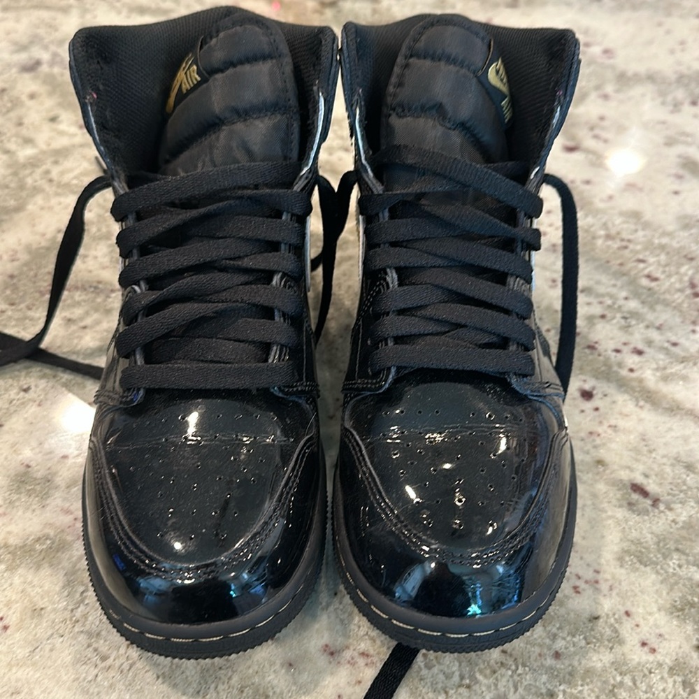 Practically new Nike Jordans black patent leather with gold accents. Size 7.